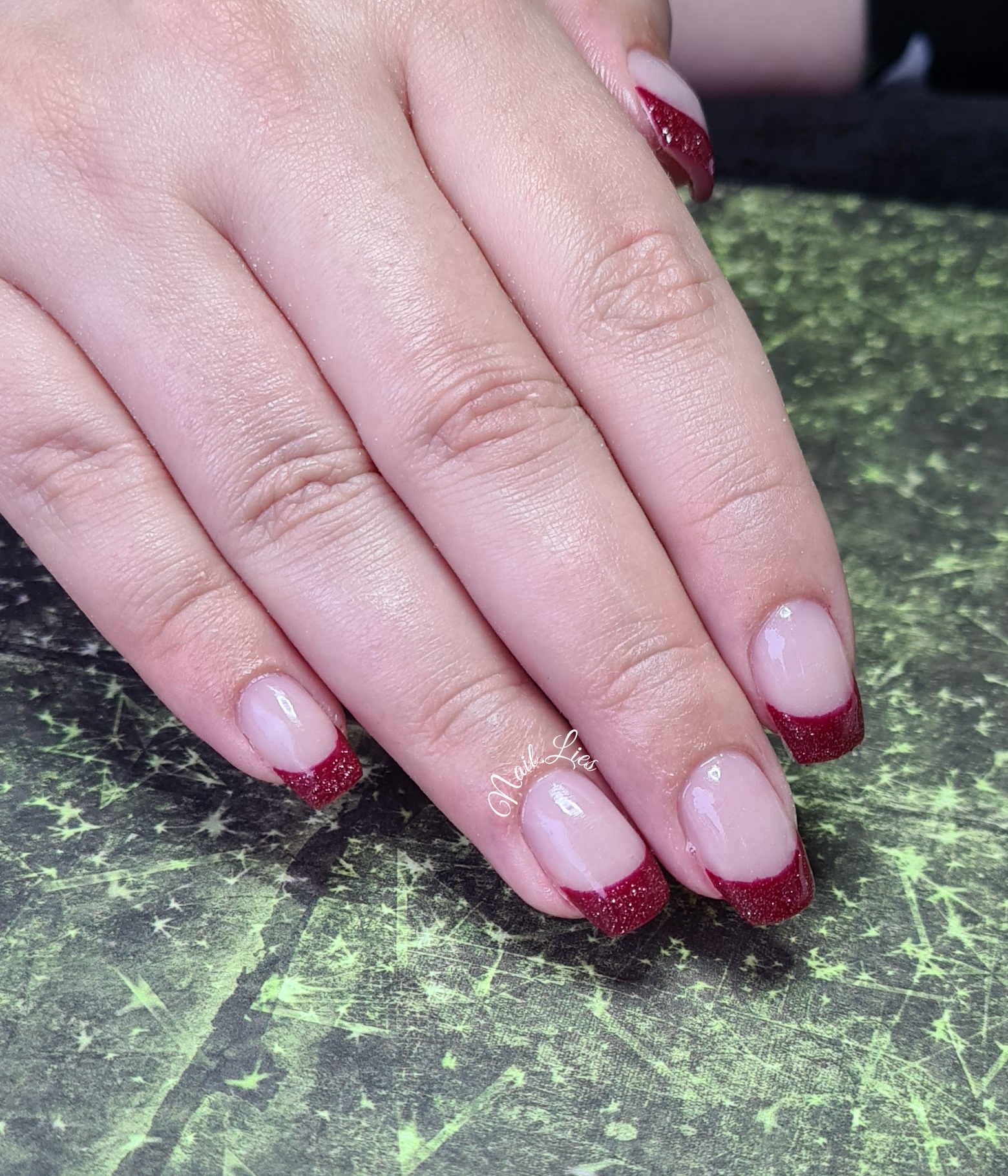 Nagels met een zachtroze basis en rode glitterrand