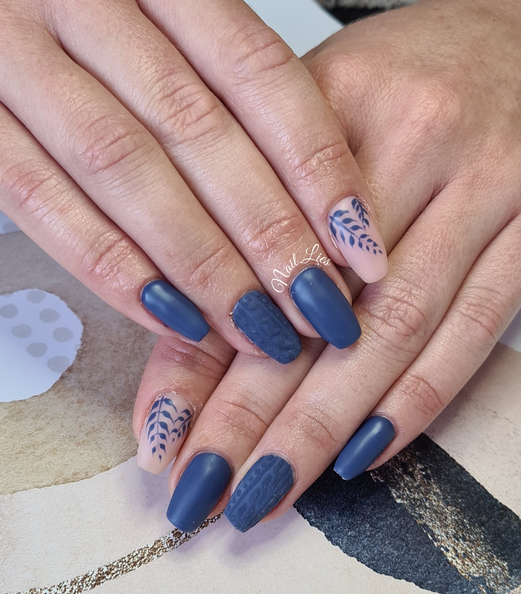 Matblauwe nagels gecombineerd met lichte nagels met een donkerblauw patroon